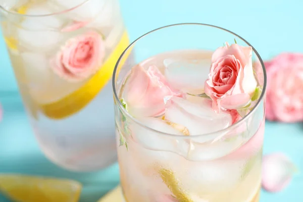 Sabrosa bebida refrescante de limón con rosas en la mesa azul claro, primer plano —  Fotos de Stock
