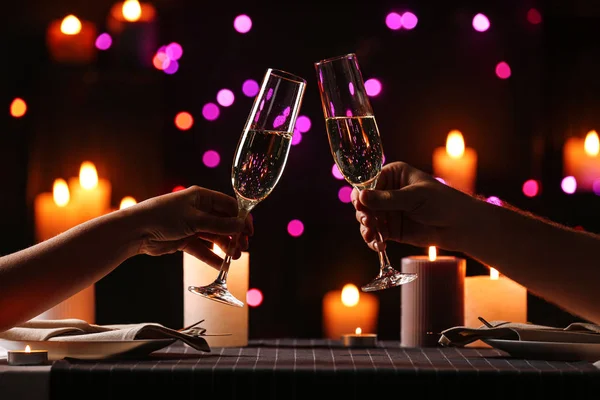 Pareja joven con copas de champán teniendo cena romántica a la luz de las velas en la mesa, primer plano — Foto de Stock