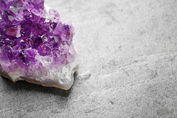 Beautiful purple amethyst gemstone on grey table, space for text — Stock Photo, Image