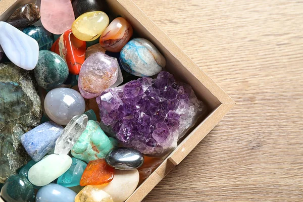 Scatola con diverse belle pietre preziose sul tavolo di legno, posa piatta — Foto Stock