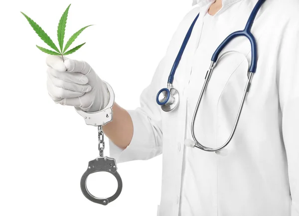 Läkare i handfängsel hålla blad av medicinsk hampa på vit bakgrund, närbild — Stockfoto