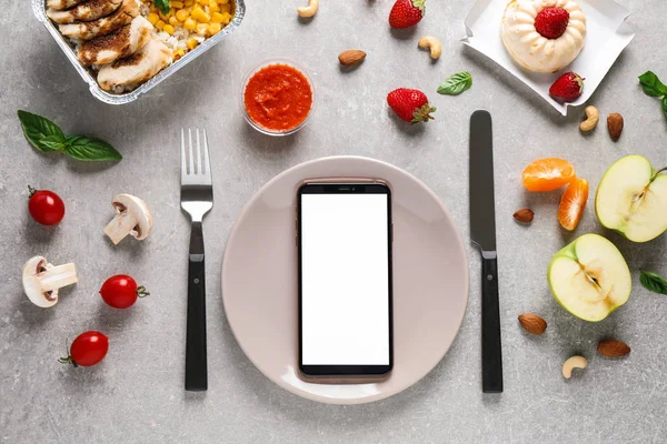 Плоский укласти композицію зі смартфоном і виробами на сірому столі, макет для дизайну. Доставка здорової їжі — стокове фото