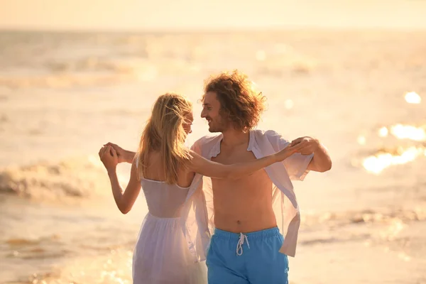 Jeune couple dansant sur la plage au coucher du soleil — Photo