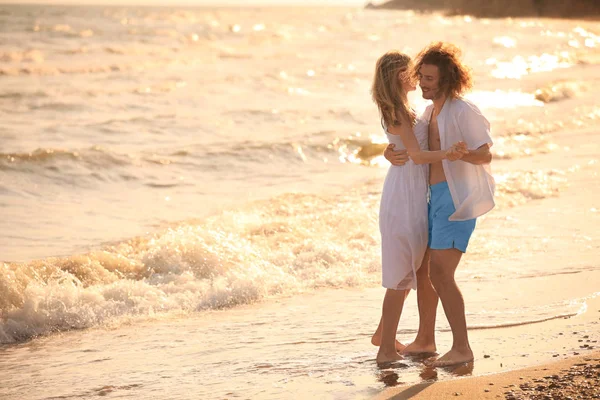 Jovem casal dançando na praia ao pôr do sol — Fotografia de Stock