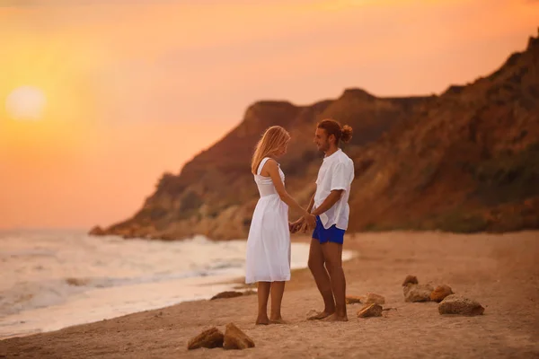 Pareja joven caminando en la playa al atardecer — Foto de Stock