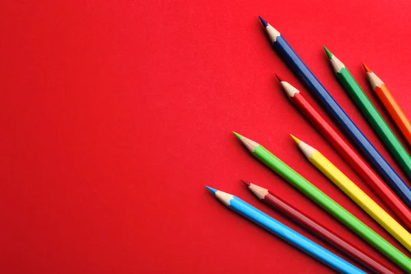 Επίπεδη σύσταση σύνθεση με χρωματιστά μολύβια σε κόκκινο φόντο. Χώρος για κείμενο — Φωτογραφία Αρχείου