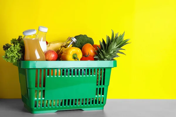 Carrello con prodotti alimentari su tavolo grigio su sfondo giallo. Spazio per testo — Foto Stock