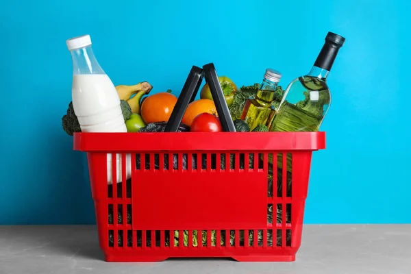 밝은 파란색 배경에 대한 회색 테이블에 식료품 과 쇼핑 바구니 — 스톡 사진