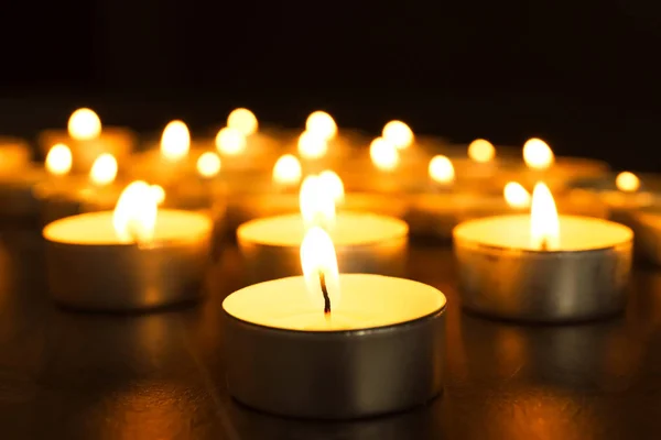 Burning candles on table in darkness, closeup. Funeral symbol — Stock Photo, Image