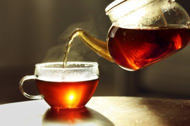 Bulanık arka plan, closeup karşı fincan içine çaydanlık taze sıcak çay dökme