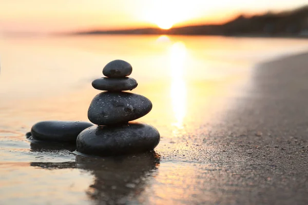 Pedras escuras na areia perto do mar ao pôr do sol, espaço para texto. Conceito Zen — Fotografia de Stock