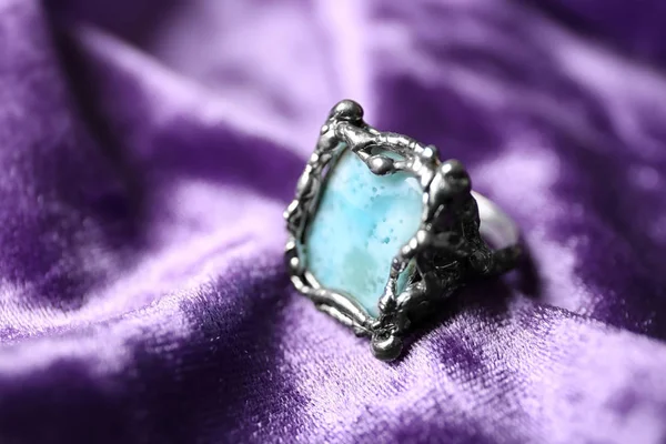 Krásný stříbrný prsten s larimarním drahokamem na fialové tkanině, zaostřená — Stock fotografie