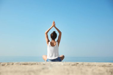 Deniz kenarında yoga yapan güzel bir genç kadın.