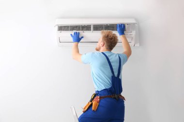 Professional technician maintaining modern air conditioner indoors clipart