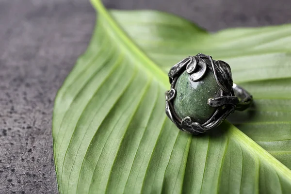 Прекрасне срібне кільце з овальним дорогоцінним камінням на зеленому листі. Простір для тексту — стокове фото