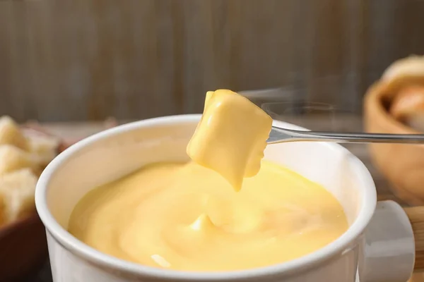 Mergulhando pão em panela com fondue de queijo na mesa, close-up — Fotografia de Stock