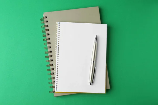Anteckningsböcker och penna på grön bakgrund, uppifrån — Stockfoto