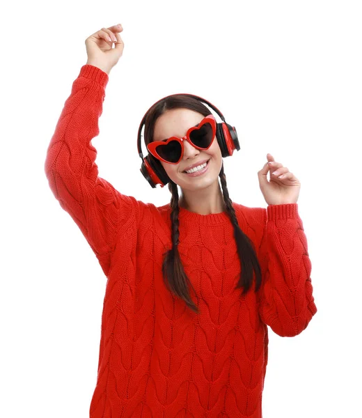 Mujer joven con gafas en forma de corazón escuchando música sobre fondo blanco —  Fotos de Stock