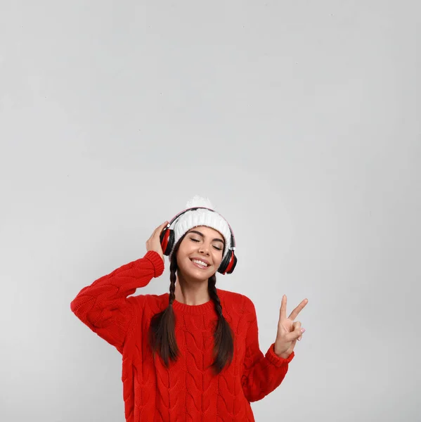 Νεαρή γυναίκα που ακούει μουσική με ακουστικά σε γκρι φόντο — Φωτογραφία Αρχείου