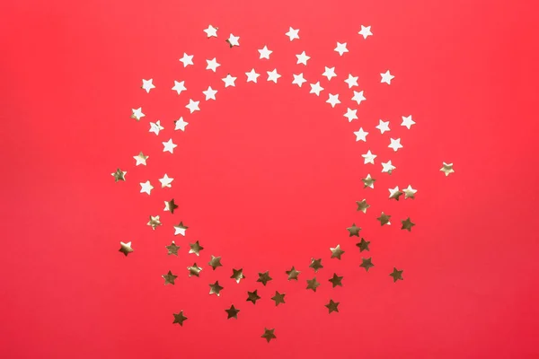 Frame made of confetti stars with space for text on red background, top view. Christmas celebration — Stock Photo, Image