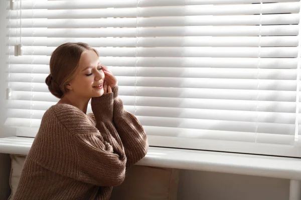 Mulher bonita perto da janela em casa, espaço para texto. Ambiente de inverno — Fotografia de Stock