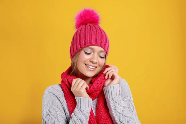 Mujer joven en suéter cálido, bufanda y sombrero sobre fondo amarillo. Temporada de invierno — Foto de Stock