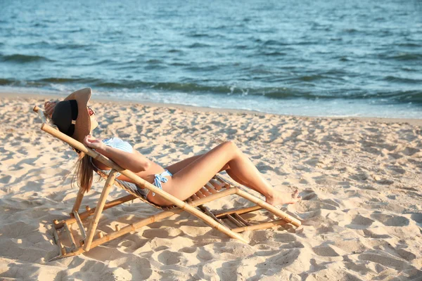 ビーチでデッキチェアでリラックスする若い女性 — ストック写真