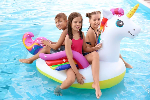 Enfants heureux sur licorne gonflable dans la piscine — Photo