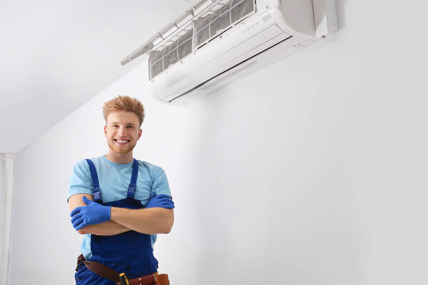 Professional technician near modern air conditioner indoors