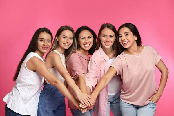 Šťastné ženy dávají dohromady ruce na růžovém pozadí. Koncepce síly dívek — Stock fotografie