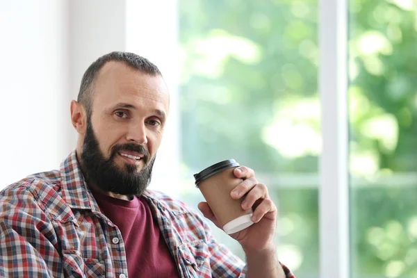 Portret van knappe volwassen man met koffie in de buurt van venster — Stockfoto