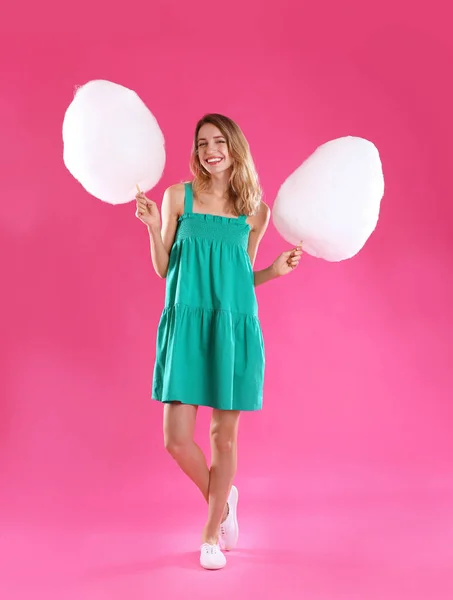 Mujer joven feliz con caramelos de algodón sobre fondo rosa — Foto de Stock