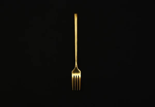 Tenedor de oro brillante sobre fondo negro, vista superior — Foto de Stock