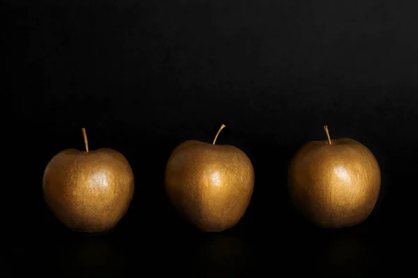 Gold painted fresh apples on black background