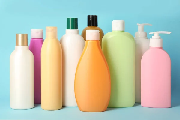 Flaschen mit verschiedenen Haarpflege-Kosmetika auf hellblauem Hintergrund — Stockfoto