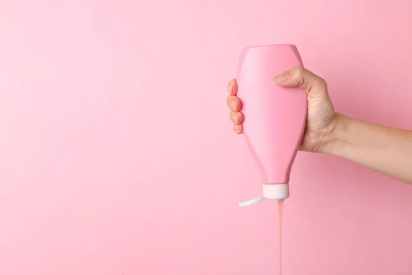 Vrouw gieten cosmetische product van fles op kleur achtergrond, close-up. Ruimte voor tekst — Stockfoto