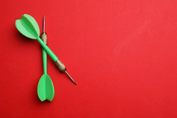 Frecce dardo verde su sfondo rosso, posa piatta con spazio per il testo — Foto Stock