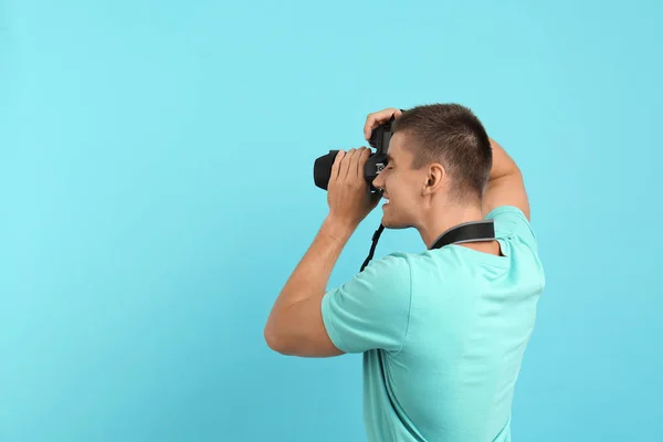 Genç profesyonel fotoğrafçı açık mavi arka plan üzerinde fotoğraf çekiyor. Metin için alan — Stok fotoğraf