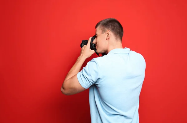 Joven fotógrafo profesional tomando fotos sobre fondo rojo. Espacio para texto —  Fotos de Stock