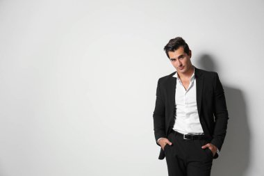 Hafif bej arka planda zarif takım elbiseli yakışıklı genç adam. Metin için alan