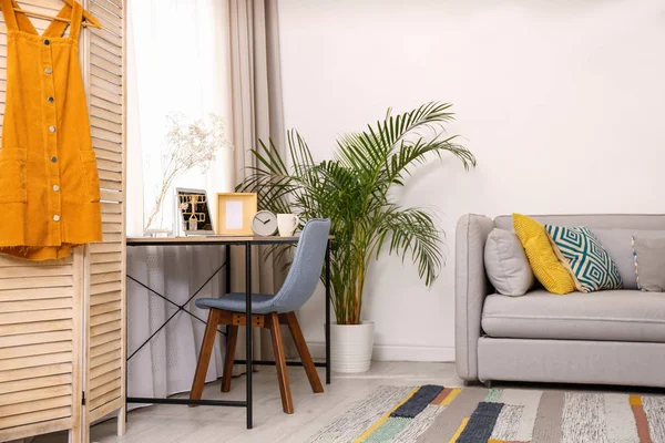 Yellow dress on wooden folding screen indoors. Interior design