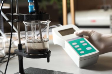 Tabloda toprağın asitliğini ve ph'ını ölçen bilim adamı, yakın çekim. Laboratuvar analizi