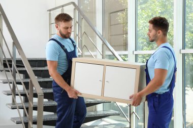 Ofiste merdivenlerde dolap taşıyan profesyonel işçiler. Taşıma hizmeti