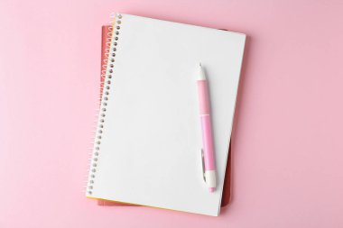 Dizüstü bilgisayarlar ve pembe arka plan üzerine kalem, üst görünüm