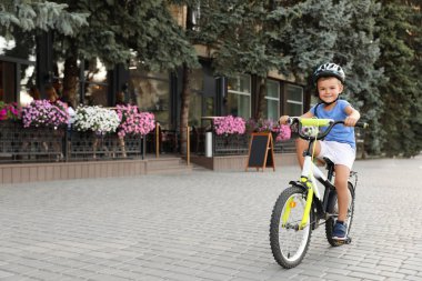 Sokakta bisiklete binen kasklı mutlu küçük çocuk