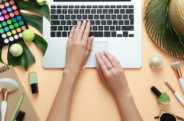 Genç güzellik blogger açık turuncu arka plan, üst görünüm üzerinde aksesuarları yakın dizüstü bilgisayar ile çalışan