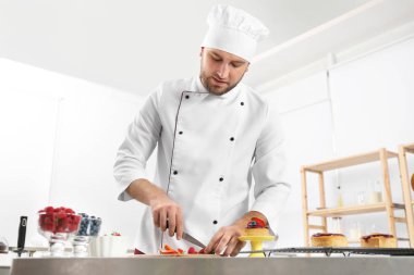 Erkek pasta şefi mutfakta masada çilek kesme