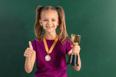 Chalkboard yakınında altın kazanan kupa ve madalya ile Mutlu kız