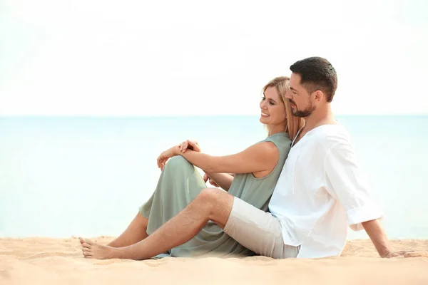 Lycklig romantiskt par sitter tillsammans på stranden — Stockfoto