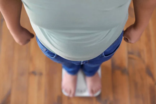 Overweight boy standing on floor scales indoors, above view — Stock Photo, Image